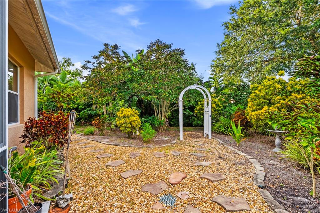 3262 Citron Drive Naples, FL 34120 - Photo 30 of 38 a backyard of a house with table and chairs under an umbrella