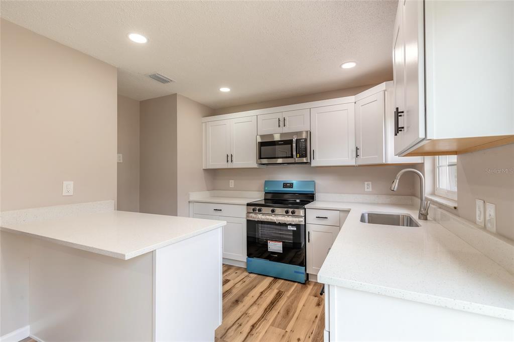 1605 Bradford Road Edgewater, FL 32132 - Photo 12 of 30 a kitchen with a sink a stove top oven and white cabinets