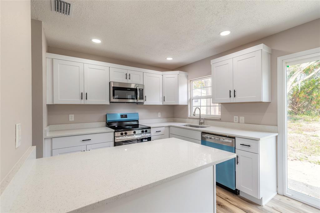 1605 Bradford Road Edgewater, FL 32132 - Photo 13 of 30 a kitchen with a sink a stove a microwave and cabinets