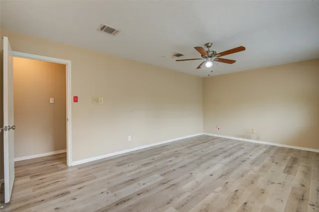 an empty room with wooden floor and ceiling fan