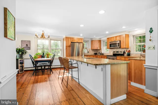 a kitchen with stainless steel appliances granite countertop a table chairs and a wooden floors