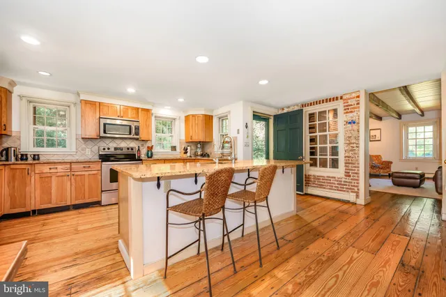 a kitchen with stainless steel appliances granite countertop a stove top oven a sink dishwasher a dining table and chairs with wooden floor