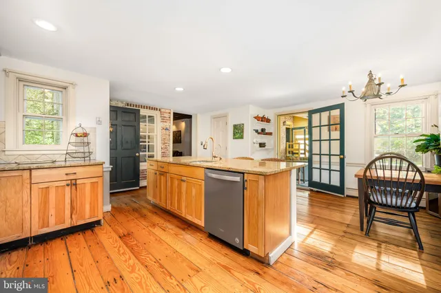 a large kitchen with kitchen island granite countertop a stove a sink and a dining table with the view of living room