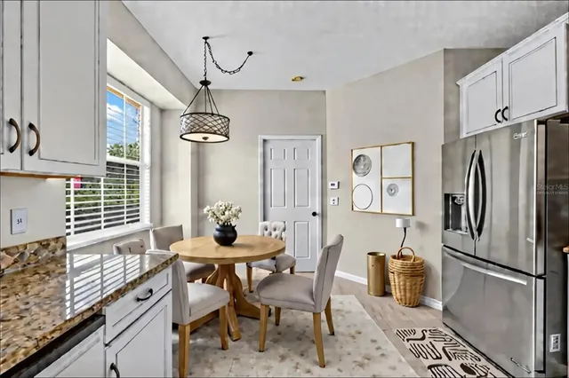 a kitchen with stainless steel appliances granite countertop a stove a refrigerator a dining table and chairs