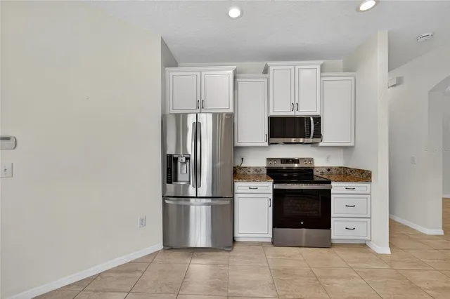 a kitchen with stainless steel appliances granite countertop a refrigerator and a stove top oven