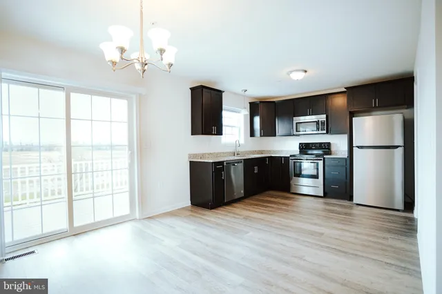 a kitchen with stainless steel appliances granite countertop a refrigerator a sink dishwasher a stove with wooden floor and cabinets