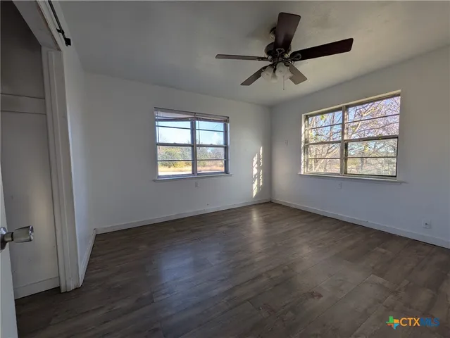 a view of an empty room with a window and wooden floor