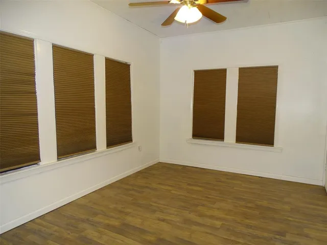 a view of an empty room with wooden floor and a chandelier fan