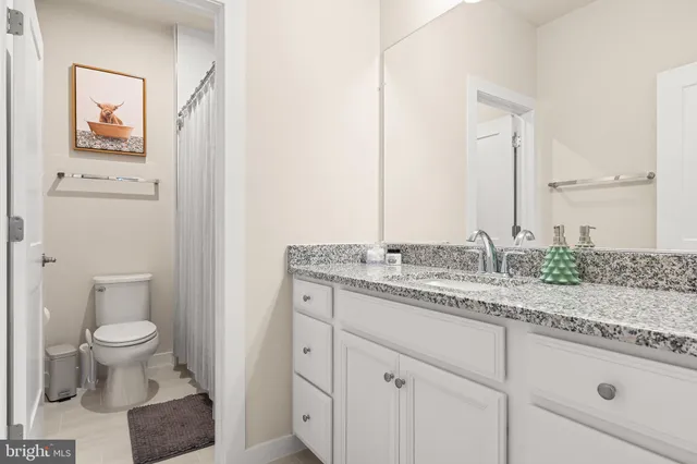 a bathroom with a granite countertop sink and a toilet