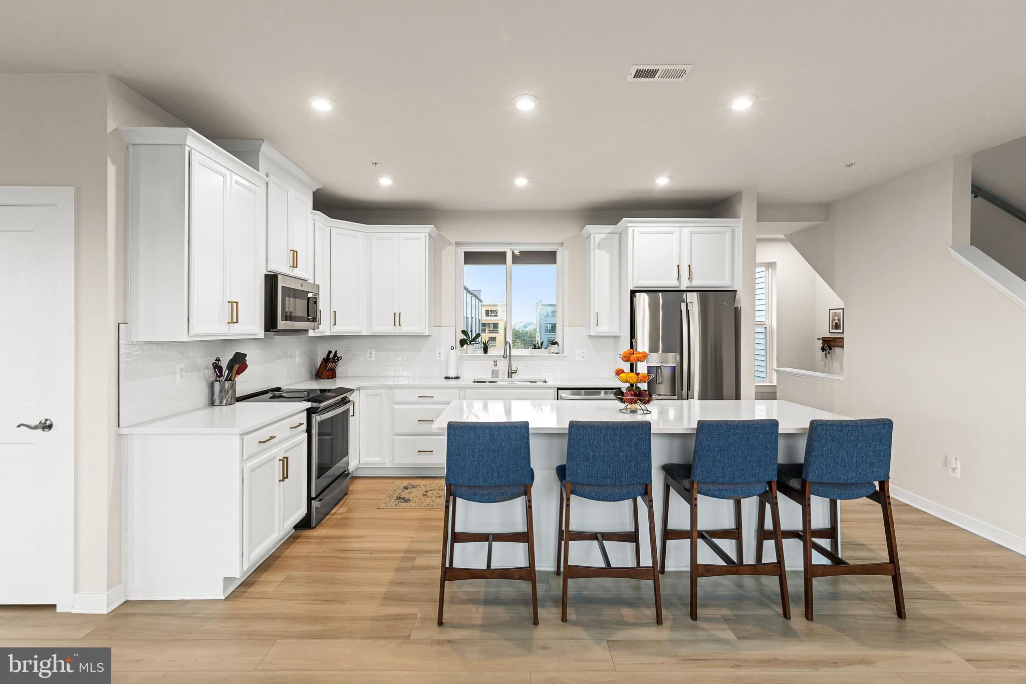 43769 Transit Square Ashburn, VA 20147 - Photo 7 of 36 a kitchen with stainless steel appliances granite countertop a stove a sink a refrigerator a kitchen island with chairs and white cabinets