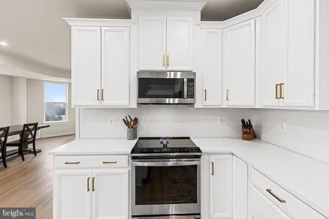 a kitchen with stainless steel appliances white cabinets and a stove a oven with white countertops
