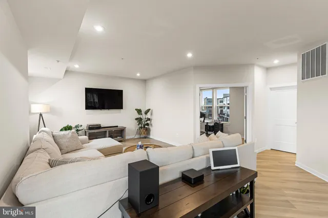 a living room with furniture a flat screen tv and a wooden floor