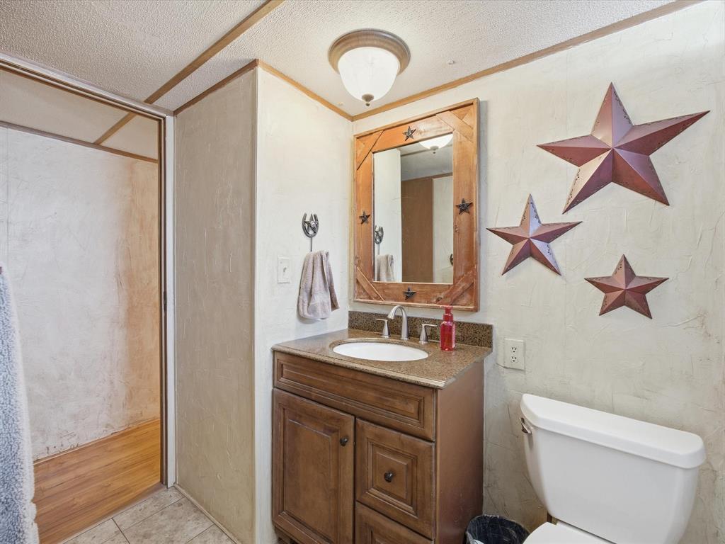 196 Perch Road Bowie, TX 76230 - Photo 20 of 33 a bathroom with a toilet sink and mirror