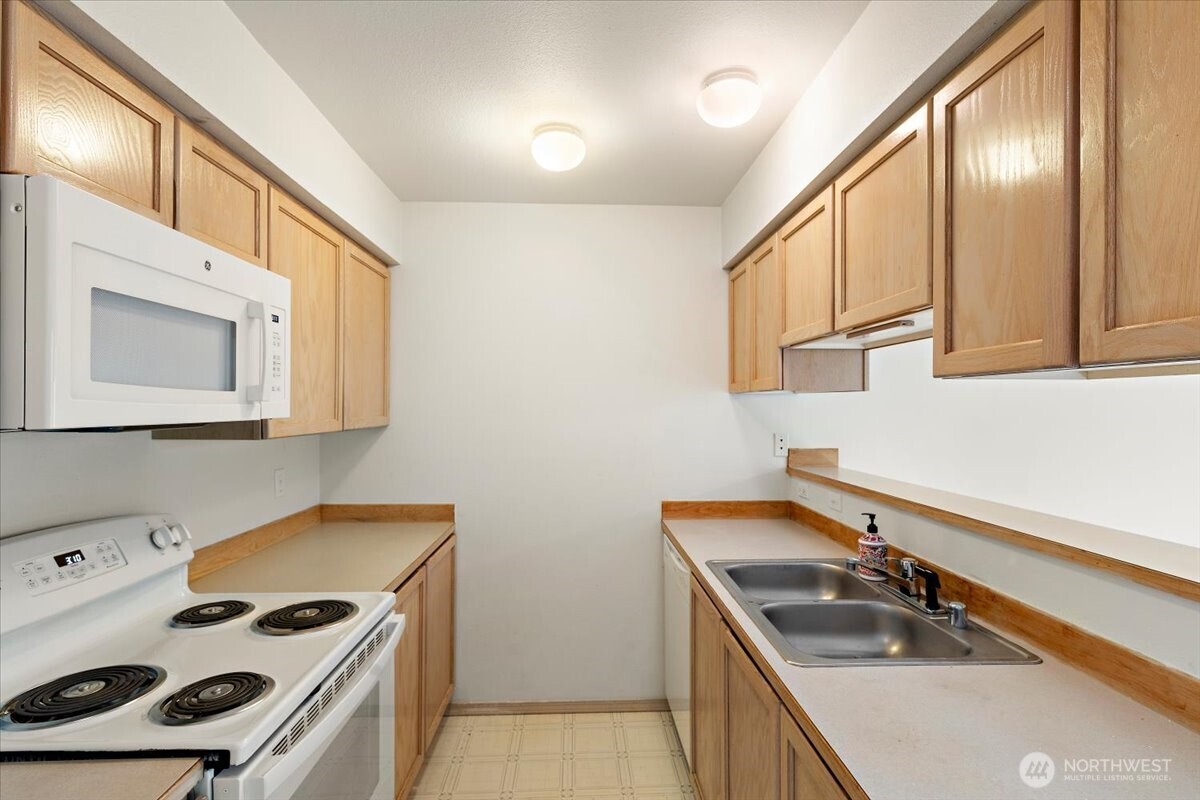 18930 Bothell Everett Highway, Unit B303 Bothell, WA 98012 - Photo 10 of 20 a kitchen that has a sink a stove and a microwave in it