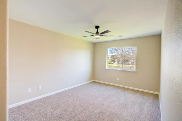 an empty room with a window and a ceiling fan