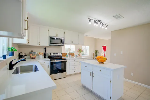a kitchen with kitchen island granite countertop a sink dishwasher stove and white cabinets