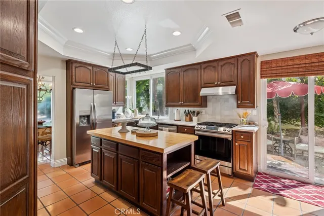 a kitchen with kitchen island granite countertop a refrigerator a sink and wooden cabinets