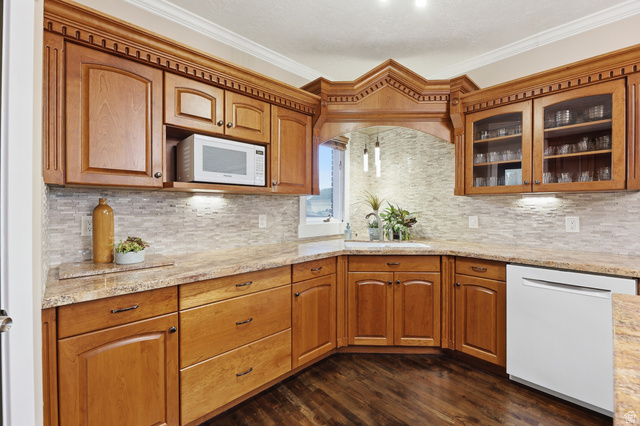 2342 Charros Road Sandy, UT 84092 - Photo 22 of 94 Kitchen featuring wood-finish cabinetry, stone-look countertops, and a full tile backsplash