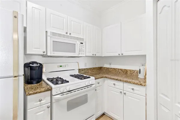 a kitchen with granite countertop white cabinets and white appliances