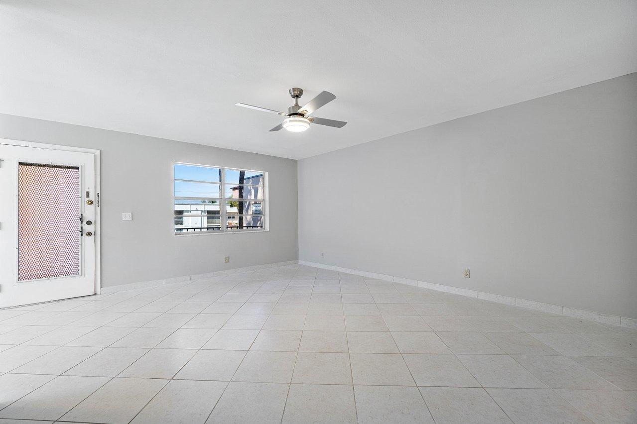 77 Normandy B Delray Beach, FL 33484 - Photo 7 of 34 an empty room with chandelier fan and windows