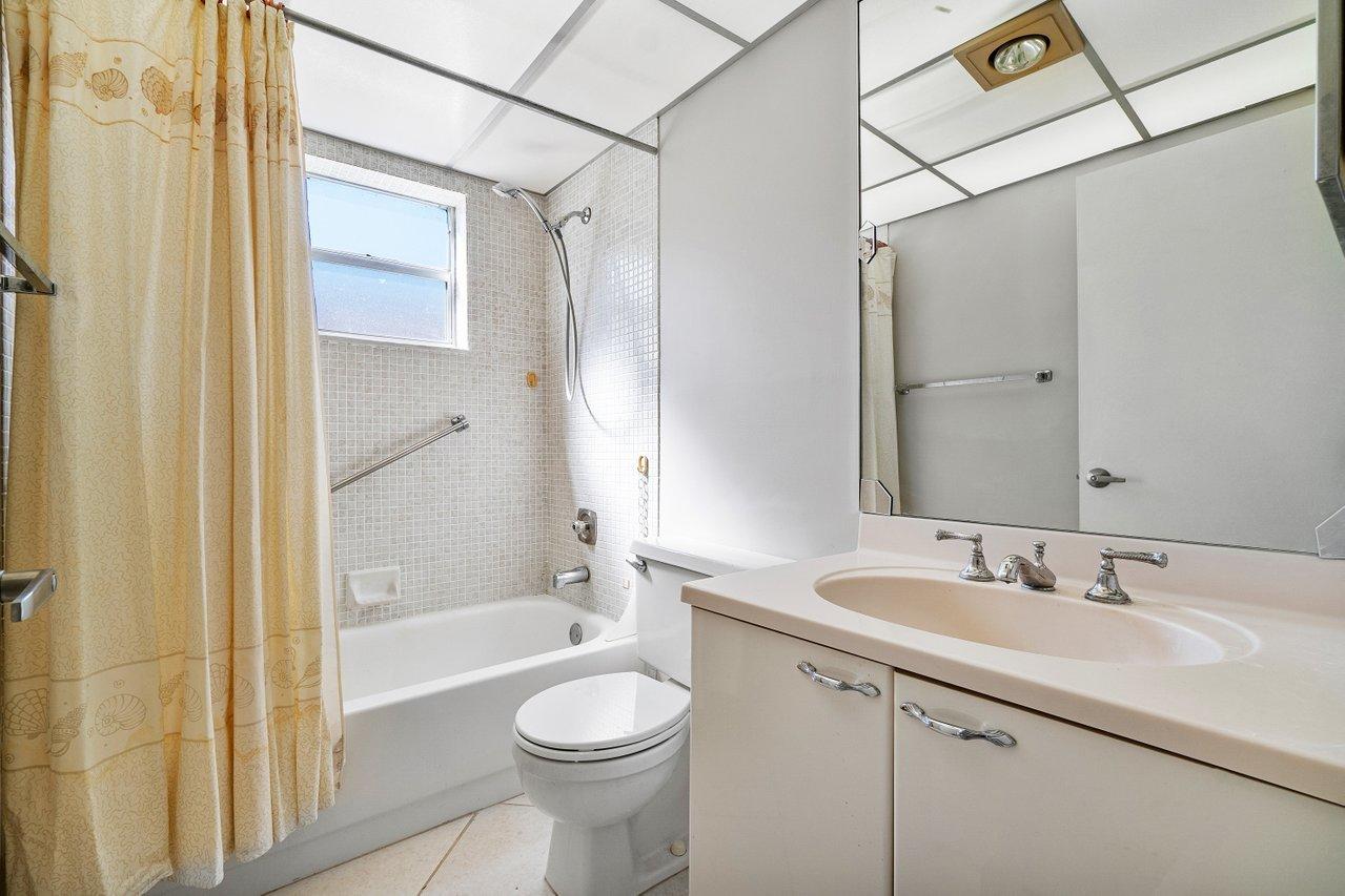 77 Normandy B Delray Beach, FL 33484 - Photo 10 of 34 a bathroom with a sink a toilet and shower