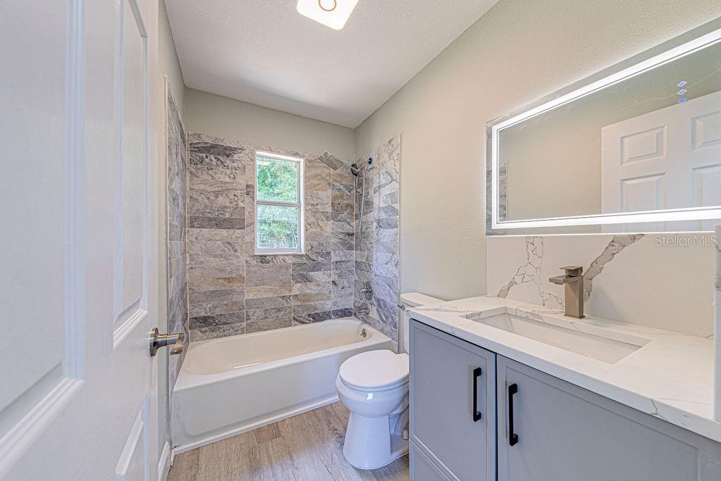 1133 Hermit Smith Road Apopka, FL 32712 - Photo 18 of 34 a bathroom with a granite countertop toilet a sink and a bathtub