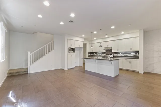 a view of kitchen with kitchen island white cabinets and stainless steel appliances