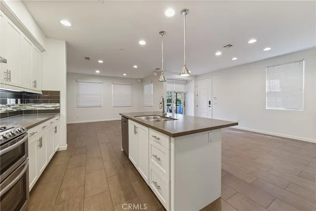 a kitchen with stainless steel appliances granite countertop a sink a stove and a refrigerator