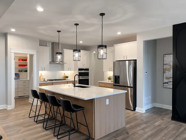 a kitchen with stainless steel appliances a dining table chairs refrigerator and microwave
