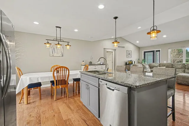 a kitchen with stainless steel appliances granite countertop a sink a window and chairs