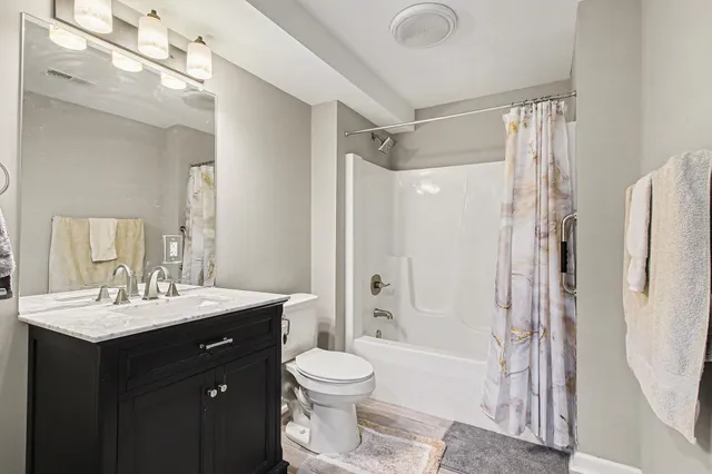 a bathroom with a double vanity sink toilet mirror and shower