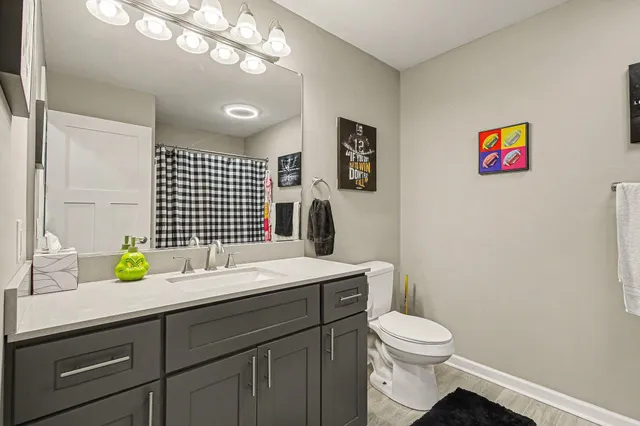 a bathroom with a granite countertop toilet sink and mirror