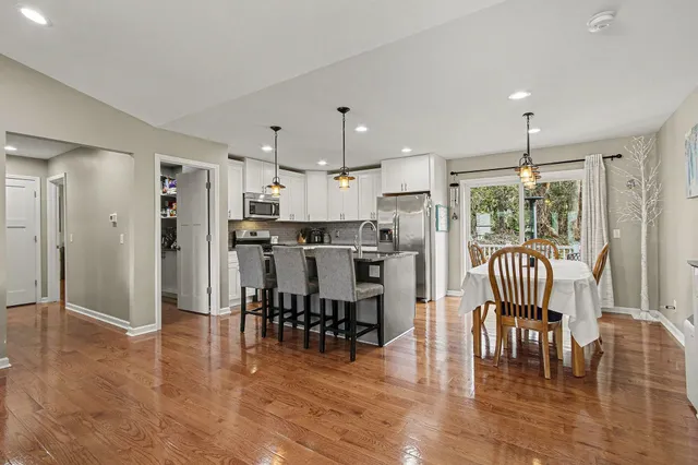an open kitchen with granite countertop a refrigerator a dining table and chairs