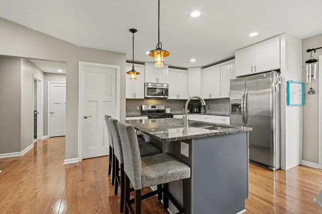 a kitchen with stainless steel appliances granite countertop a table chairs refrigerator and microwave