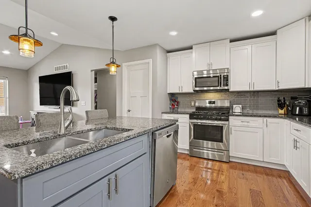 a kitchen with granite countertop a sink a counter top space appliances and cabinets