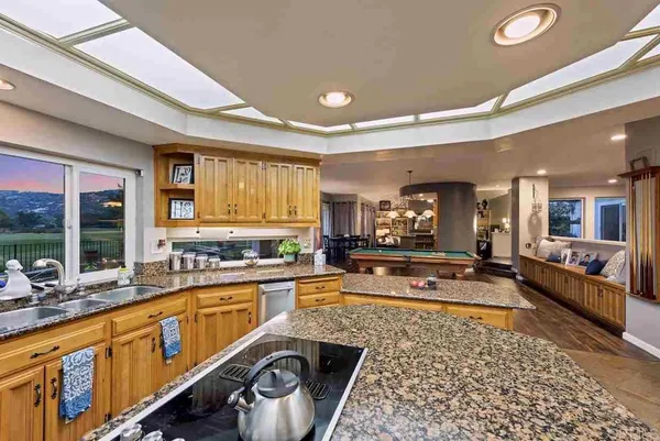 a kitchen with stainless steel appliances kitchen island granite countertop a sink refrigerator and cabinets