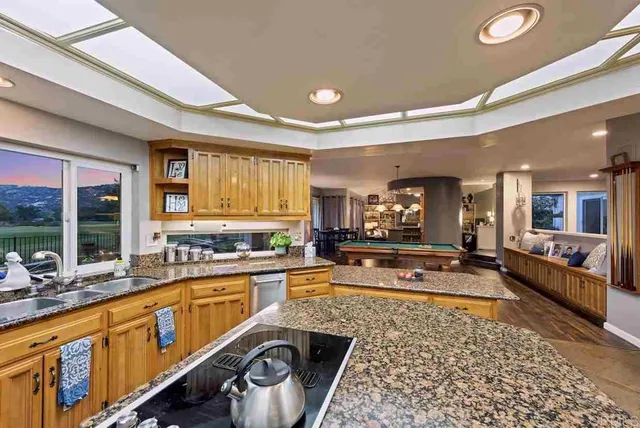 a kitchen with stainless steel appliances kitchen island granite countertop a sink refrigerator and cabinets