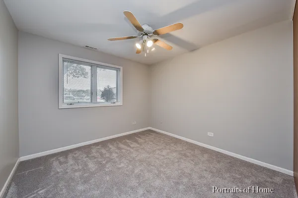 an empty room with window and ceiling fan