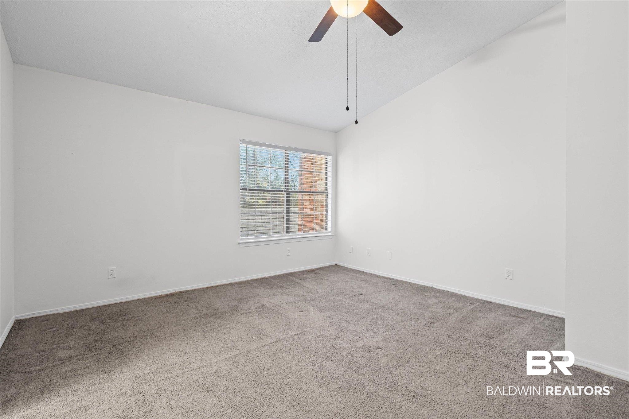 5900 Grelot Road, Unit 504 Mobile, AL 36609 - Photo 11 of 24 Carpeted spare room featuring vaulted ceiling and ceiling fan