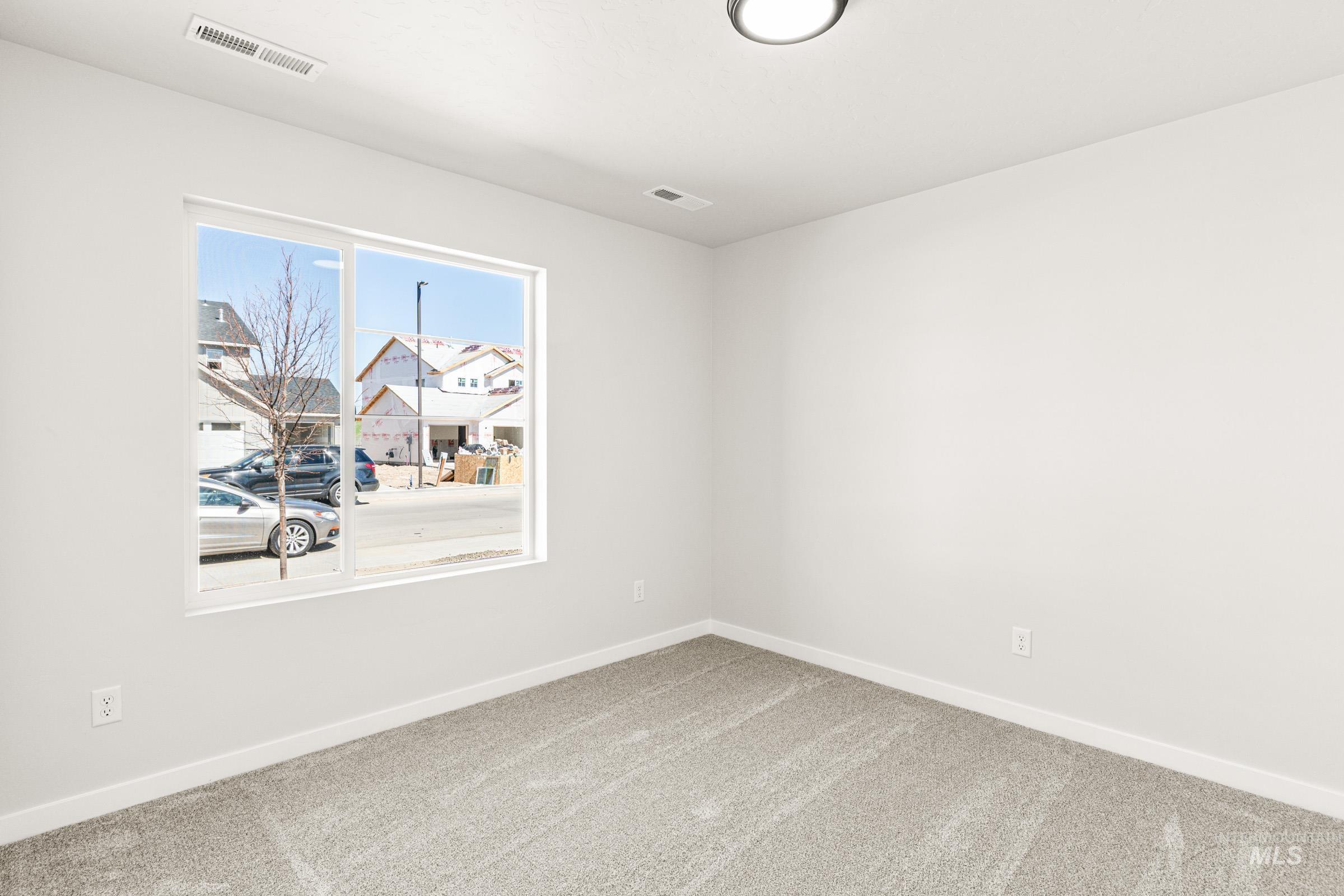 1077 West Jasper Street Meridian, ID 83642 - Photo 11 of 19 Spacious room featuring a large window, neutral carpeting, white baseboards, and a flush-mount ceiling light fixture