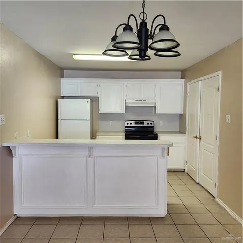 a kitchen with a refrigerator a stove and white cabinets