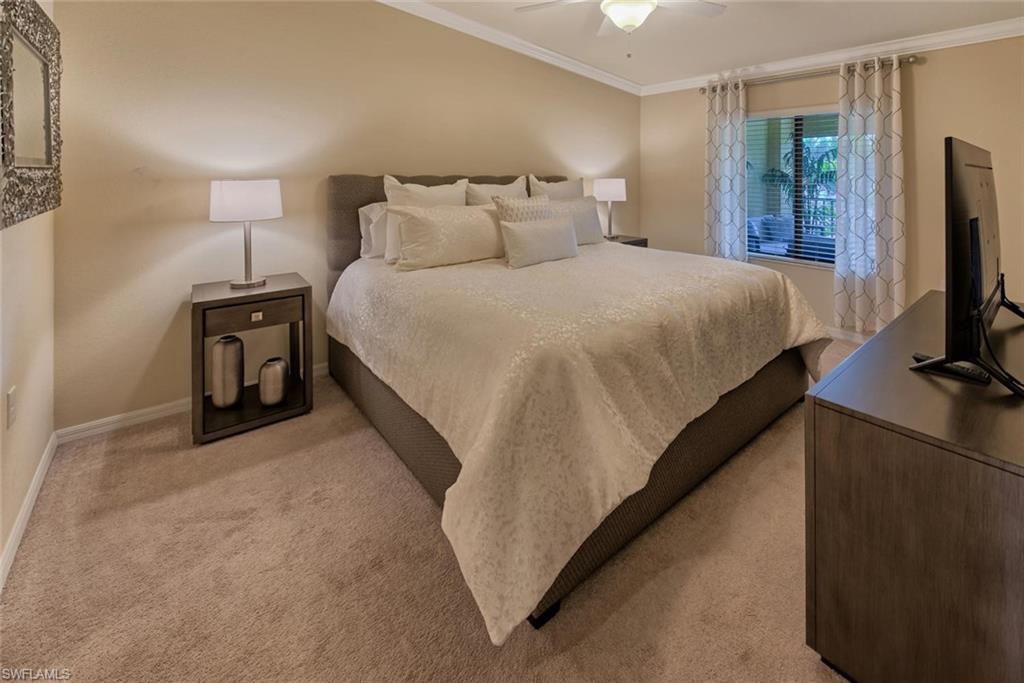 9513 Avellino Way, Unit 2024 Naples, FL 34113 - Photo 15 of 33 a bedroom with a bed and a flat tv screen on a dresser