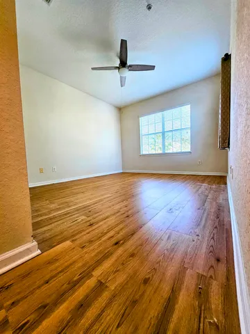 a view of empty room with wooden floor and fan