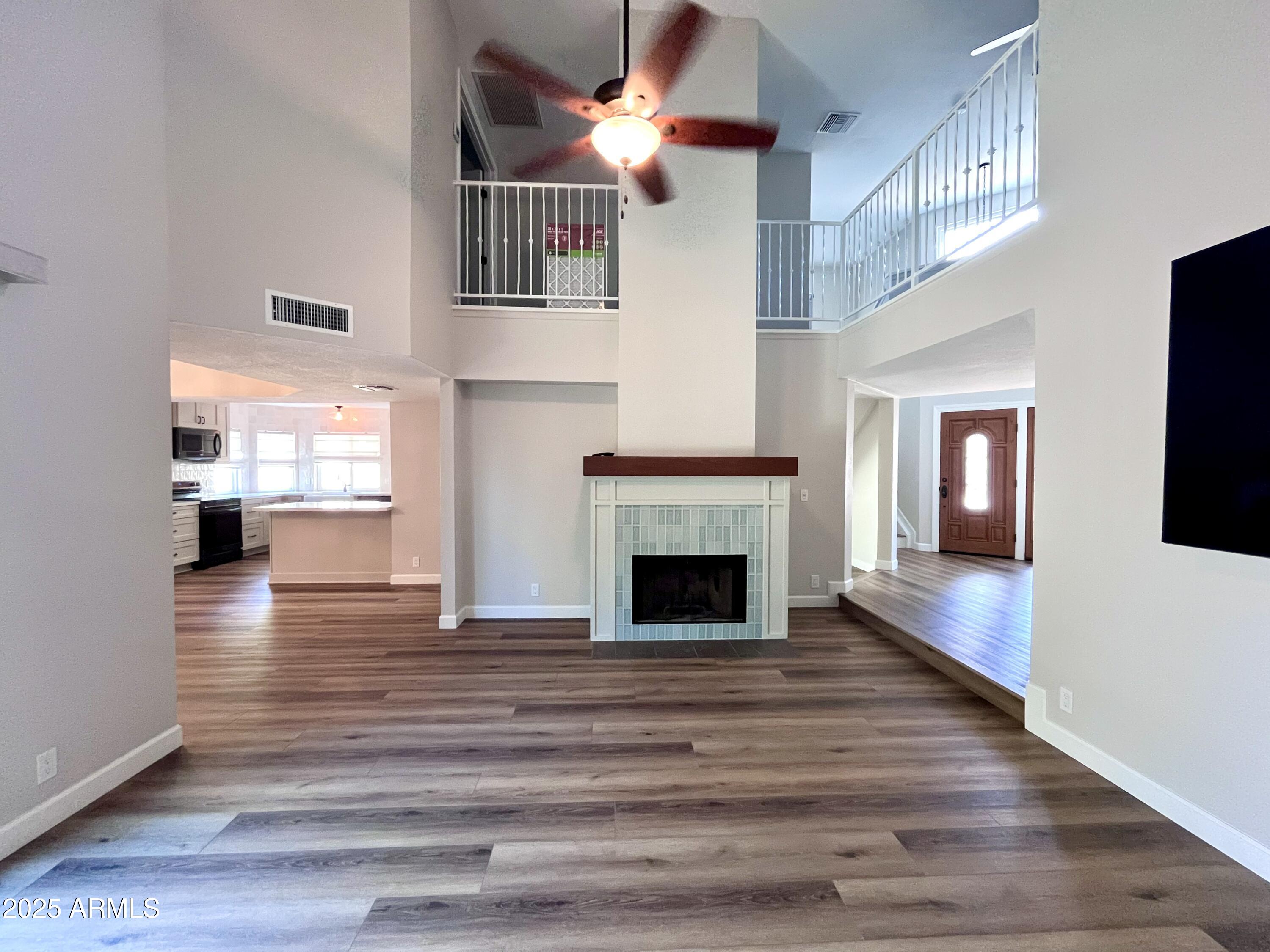 a view of an empty room with wooden floor fireplace and a window