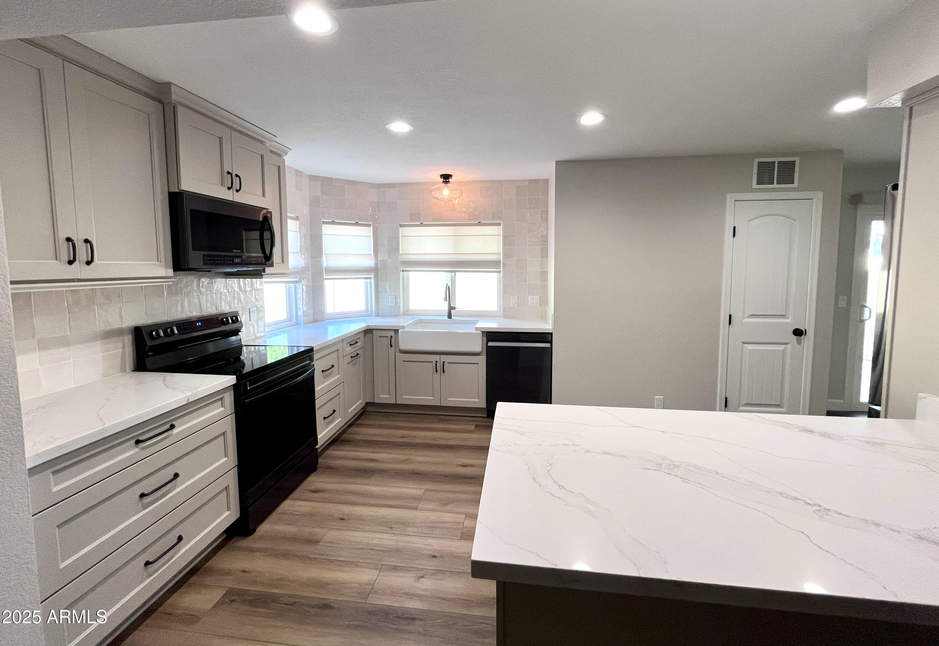 4924 East Hillery Drive Scottsdale, AZ 85254 - Photo 12 of 24 a kitchen with stainless steel appliances kitchen island granite countertop a stove top oven a sink dishwasher and a refrigerator with wooden floor