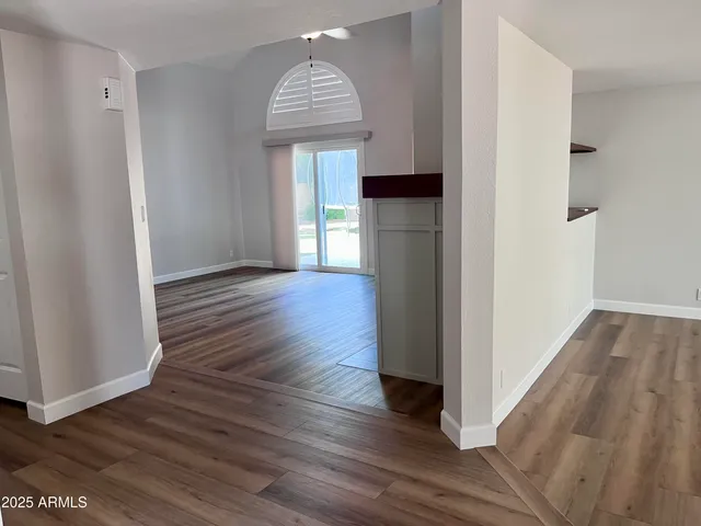 a view of empty room with wooden floor and window