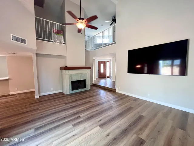 a view of a livingroom with a fireplace a ceiling fan and wooden floor