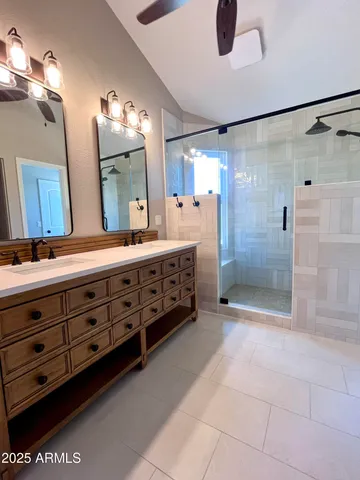 a bathroom with a double vanity sink a toilet a mirror and shower