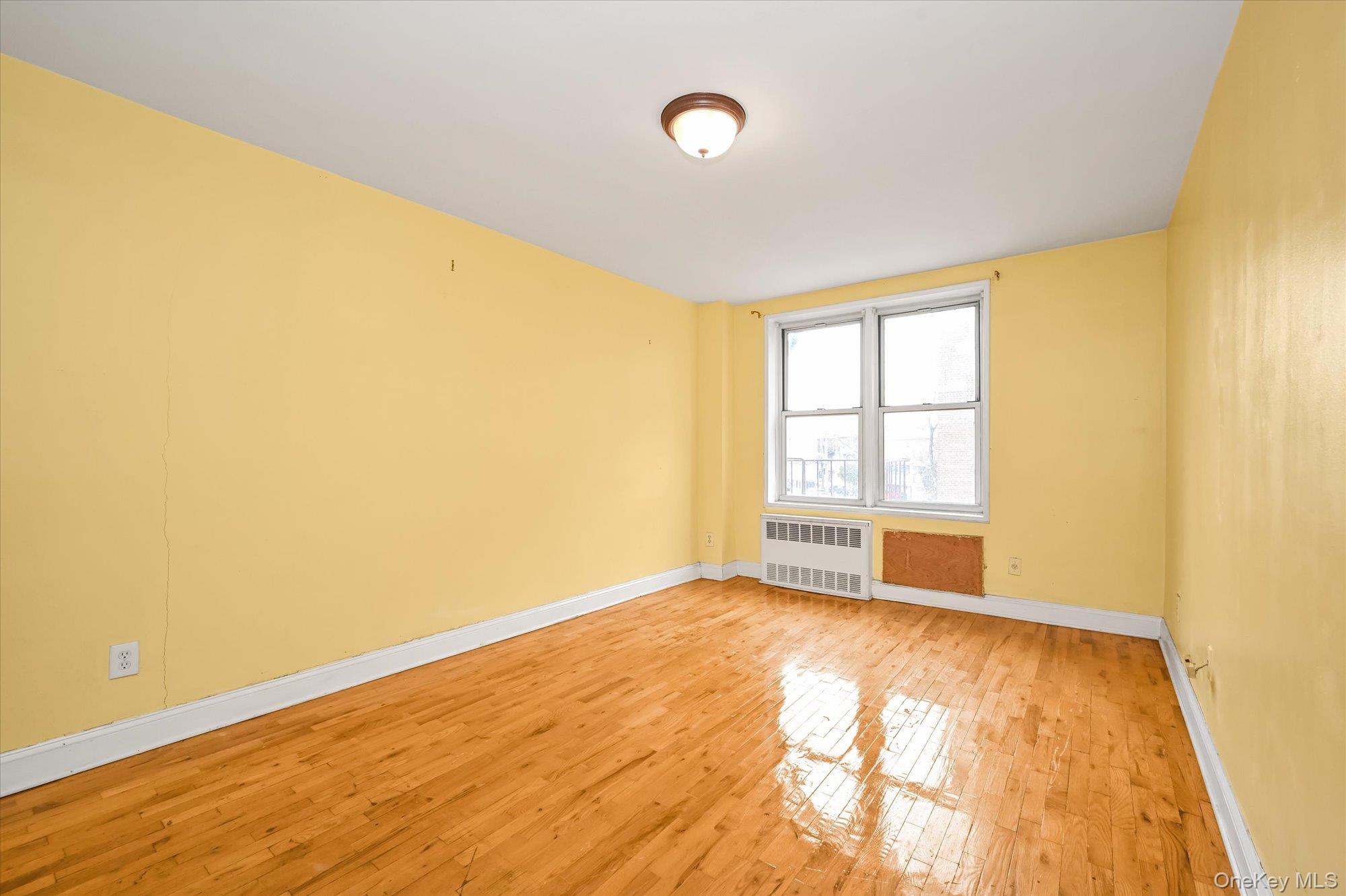 59-30 108th Street, Unit 4P Queens, NY 11368 - Photo 12 of 18 a view of an empty room with a window and wooden floor
