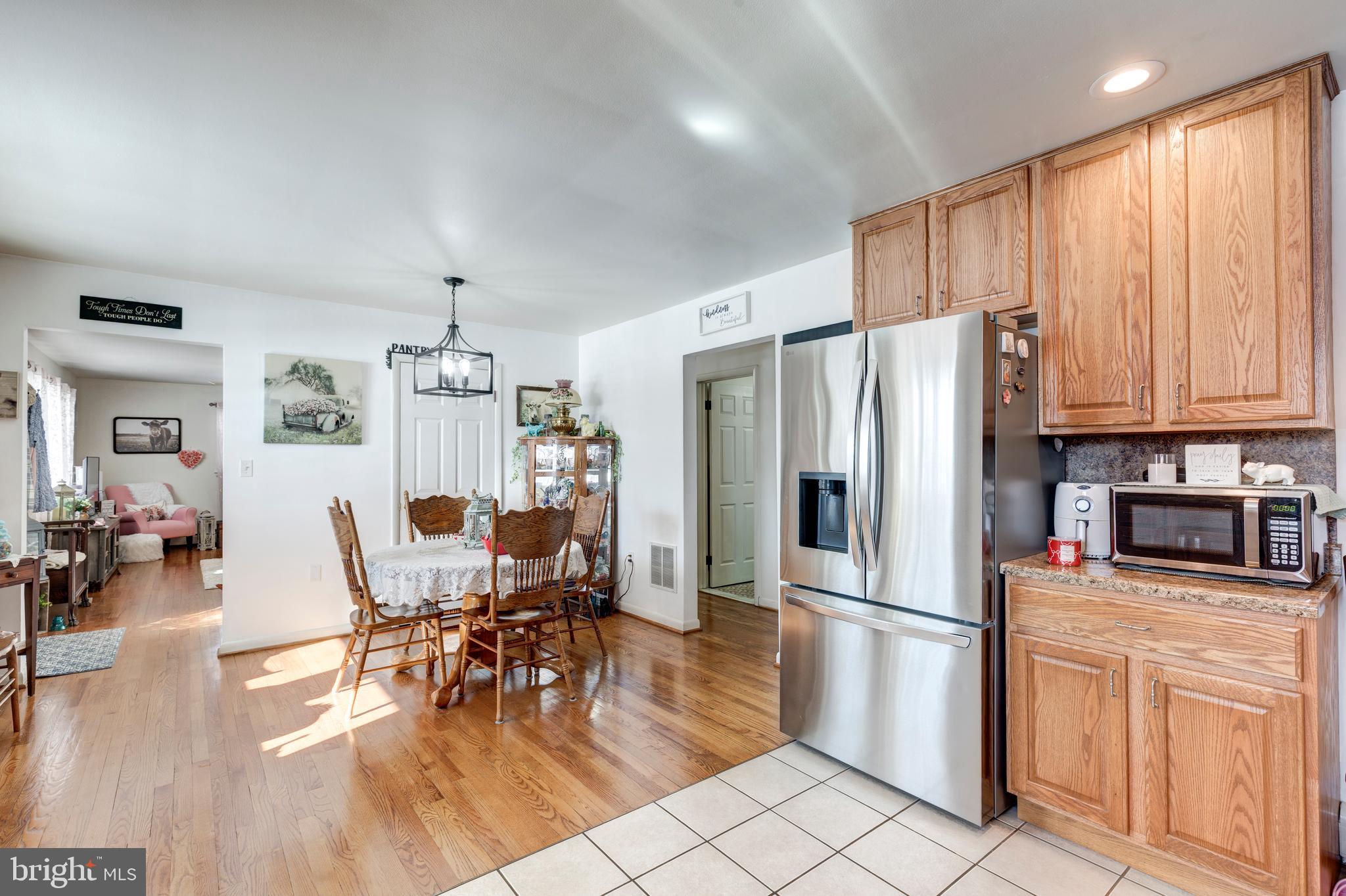 3820 Kump Station Road Taneytown, MD 21787 - Photo 8 of 59 a kitchen with stainless steel appliances granite countertop a refrigerator a stove top oven a sink dishwasher and white cabinets with wooden floor